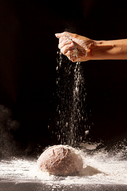 hand-pours-flour-baked-bread